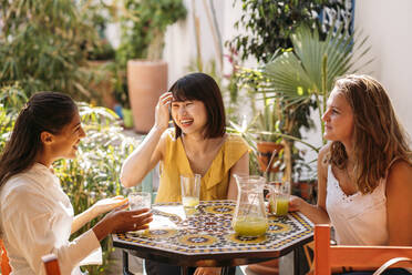 Three happy female friends meeting in a cafe drinking lemonade - MPPF00133