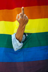 Woman giving the finger in front of a rainbow flag - OCMF00803