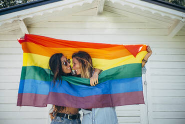 Two smiling women holding up a rainbow flag - OCMF00810