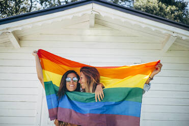 Two smiling women holding up a rainbow flag - OCMF00811