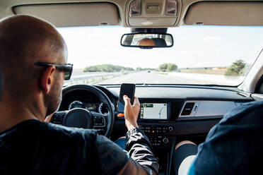 Man sitting in a car using his smartphone - CJMF00149