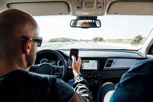 Mann sitzt in einem Auto und benutzt sein Smartphone - CJMF00149