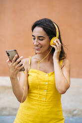 Schöne junge Frau mit Kopfhörern und Mobiltelefon - MPPF00160