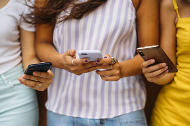 Nahaufnahme von drei jungen Frauen, die Smartphones benutzen - MPPF00166