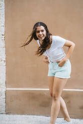 Happy young woman standing in front of a wall - MPPF00167