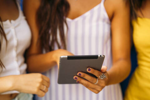 Nahaufnahme von drei jungen Frauen, die sich ein Tablet teilen, lizenzfreies Stockfoto