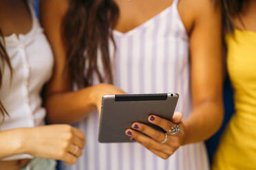 Close-up of three young women sharing a tablet - MPPF00177