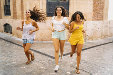 Three happy female friends running in the city - MPPF00182