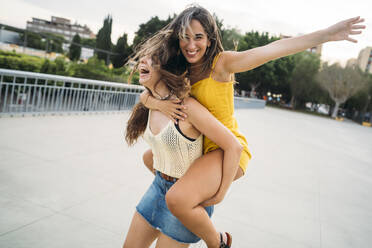 Playful young woman carrying friend piggyback - MPPF00194