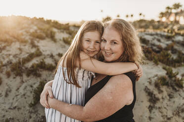 Side view of mother and redheaded elementary age daughter at sunset - CAVF65542