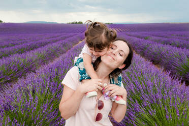 Mutter und Tochter spazieren zwischen Lavendelfeldern im Sommer - CAVF65572