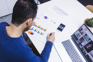 Man working on documents at desk in office - CAVF65581