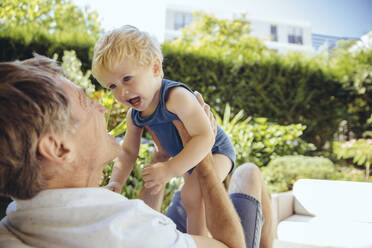 Father sitting in garden, playing with his little son - MFF04915