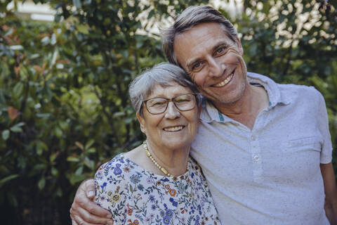 Glückliche Mutter und erwachsener Sohn im Garten, lizenzfreies Stockfoto