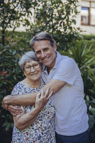 Erwachsener Sohn umarmt seine Mutter im Garten, lizenzfreies Stockfoto