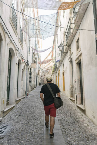 Tourist beim Spaziergang in einer Gasse in der Altstadt von Coimbra, Portugal, lizenzfreies Stockfoto