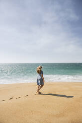 Rear view of woman walking on the beach, Nazare, Portugal - AHSF00927