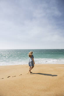 Rear view of woman walking on the beach, Nazare, Portugal - AHSF00927