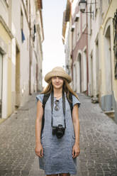 Porträt einer Frau mit Kamera in einer Gasse in der Altstadt von Coimbra, Portugal - AHSF00932