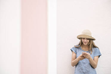 Woman standing at a wall using smartphone - AHSF00933