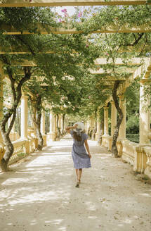Rückansicht einer Frau, die in einem schönen Park mit vielen Pflanzen spazieren geht, Aveiro, Portugal - AHSF00938