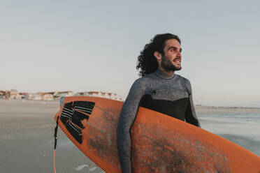 Porträt eines Surfers am Strand bei Sonnenuntergang, Costa Nova, Portugal - AHSF00955