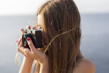 Close up of a female teenager taking a photo outdoors - JPTF00340