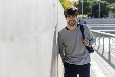 Portrait of smiling man with backpack having a break in the city - GIOF07225