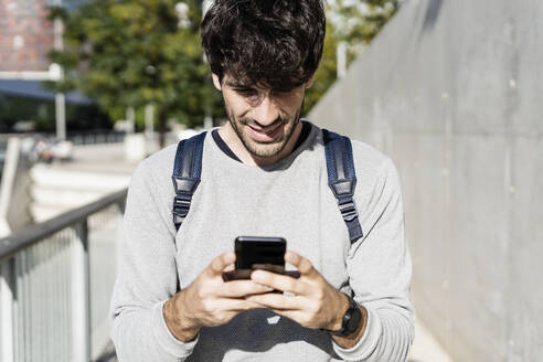 Lächelnder Mann mit Smartphone in der Stadt - GIOF07233