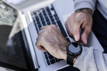 Close-up of man with smartwatch and laptop - GIOF07244