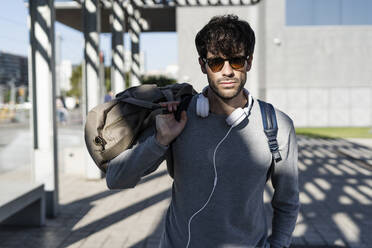 Cooler Mann mit Reisetasche in der Stadt - GIOF07261