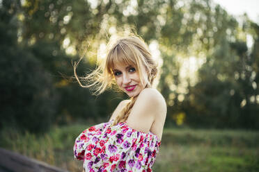 Portrait of happy young woman wearing summer dress with floral design in nature - MTBF00031