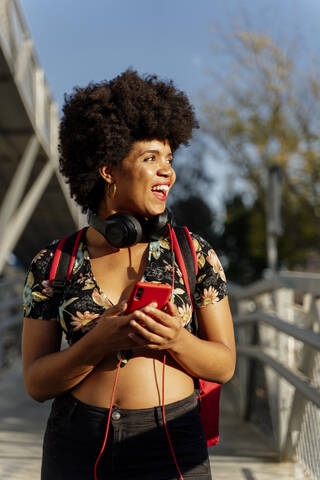 Afroamerikanerin mit Kopfhörern und Smartphone beim Musikhören, lizenzfreies Stockfoto