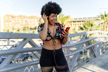 Afroamerikanerin mit Kopfhörern und Smartphone beim Musikhören - ERRF01741