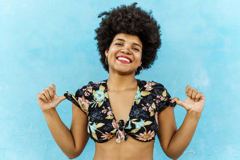 Smiling Afro-American woman in front of a blue wall - ERRF01763