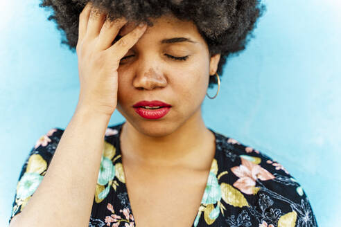Portrait of Afro-American woman, hand on forehead, blue wall in the background - ERRF01769
