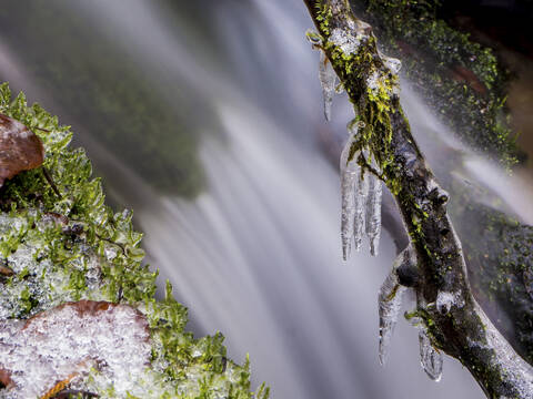 Deutschland, Bayern, Eisbedeckte Äste vor plätscherndem Wasserfall, lizenzfreies Stockfoto