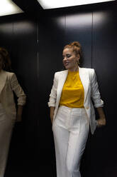 Businesswoman in white pant suit in elevator - ERRF01799