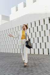 Businesswoman in white pant suit, walking in the city, talking on the phone - ERRF01804