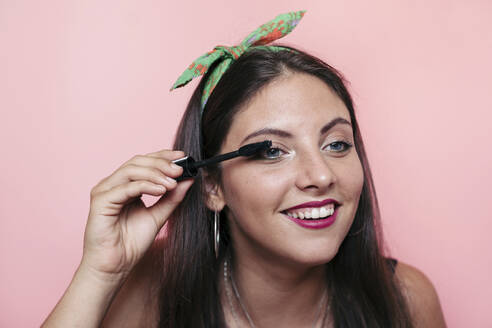 Young woman applying eyelash serum and smiling - LOTF00079