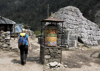 Junge Frau geht an Gebetsmühle vorbei, Manjo, Solo Khumbu, Nepal - ALRF01580