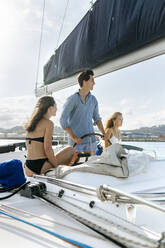 Drei junge Freunde, die einen Sommertag auf einem Segelboot genießen - MGOF04155