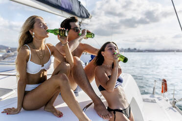Drei junge Freunde, die einen Sommertag auf einem Segelboot genießen - MGOF04170