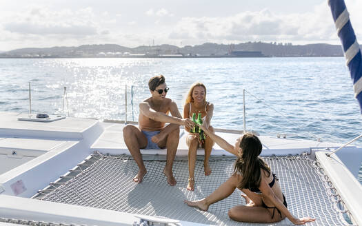 Drei junge Freunde, die einen Sommertag auf einem Segelboot genießen - MGOF04174