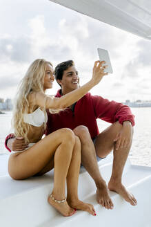 Junges Paar genießt einen Sommertag auf einem Segelboot - MGOF04194