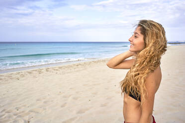 Smiling young woman standing on a beach - EPF00611
