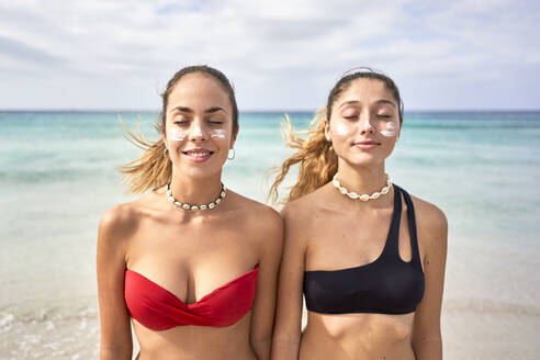 Zwei junge Frauen stehen mit geschlossenen Augen am Strand - EPF00622