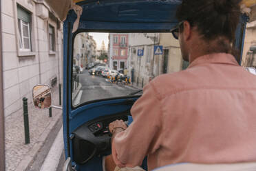 Blick von hinten auf einen Tuk-Tuk-Fahrer in der Stadt, Lissabon, Portugal - AHSF00985