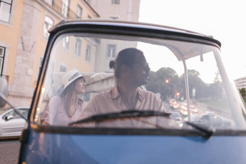 Tuk tuk driver providing tour of the city to a tourist, Lisbon, Portugal - AHSF00989