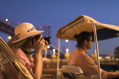 Tourist taking a photo with a camera in a tuk tuk at night, Lisbon, Portugal - AHSF00992